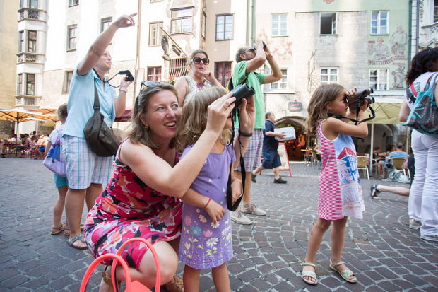 Verena Brown zeigt Kindern bei der „Weitsicht-Führung“ mit Ferngläsern die Details am Prunkerker des Goldenen Dachls.