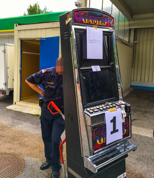 Ein Polizist transportiert einen Automaten ab.