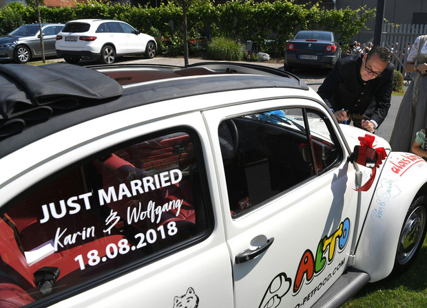 Das Hochzeitspaar bekam einen restaurierten weißen VW Käfer geschenkt, auf dem alle Festgäste unterschrieben, darunter auch Putin, der auch ein Herz zeichnete.