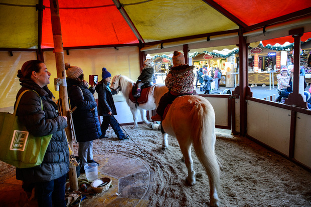 Kinder reiten auf Ponys im Ponykarussell.