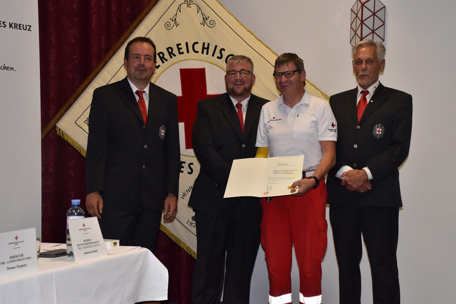 Bezirksrettungskommandant Andreas Inwinkl (l.), Bezirksstellenleiter Jürgen Ginther und Tirols RK-Präsident Günther Ennemoser (r.) haben Johann Malli in die Mitte genommen. Er ist 40 Jahre beim Roten Kreuz.