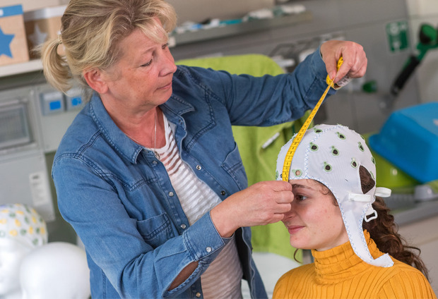 Die medizintechnische Assistentin Gabi Schöns richtet eine Haube mit Elektroden zur Messung der Hirnströme im Labor für Neurobiologie am Leibniz-Institut bei einer Probandin ein.