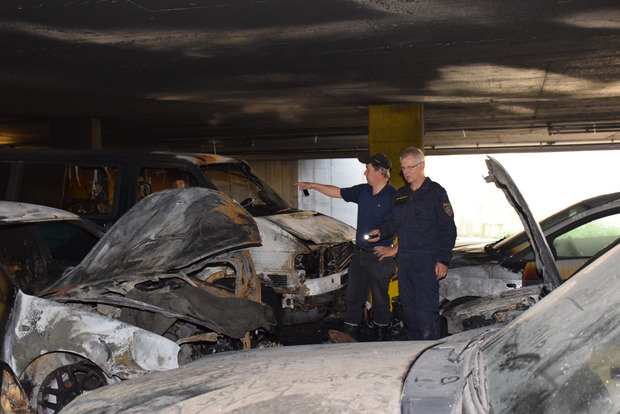 Die Brandermittler Josef Rohregger (l.) und Roland Egger suchen inmitten der ausgebrannten Wracks nach Spuren zur Brandursache.