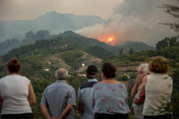 Bewohner betrachten den Brand, der sich in dem Gebiet gefährlich ausgebreitet hat.