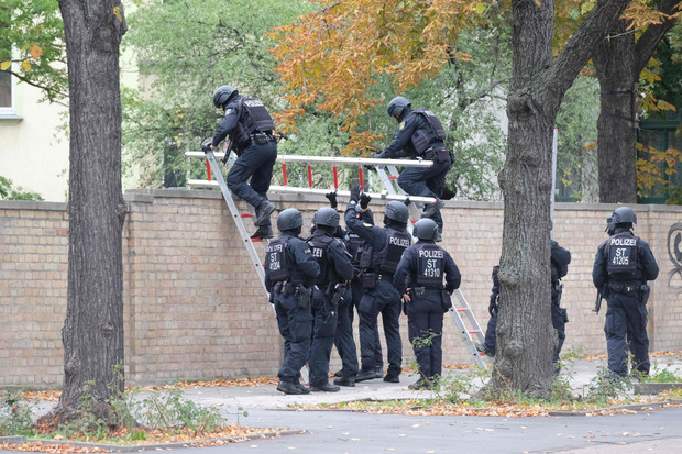 Polizisten klettern über die Mauer des Jüdischen Friedhofs in Halle.