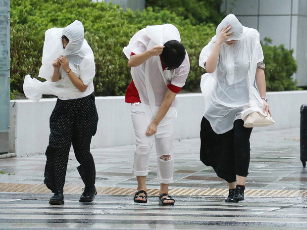 Menschen versuchen in Nagoya gegen den starken Wind anzukommen.