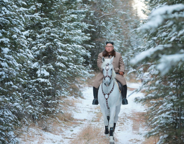 Auf dem weißen Pferd reitet Kim durch einen verschneiten Wald.