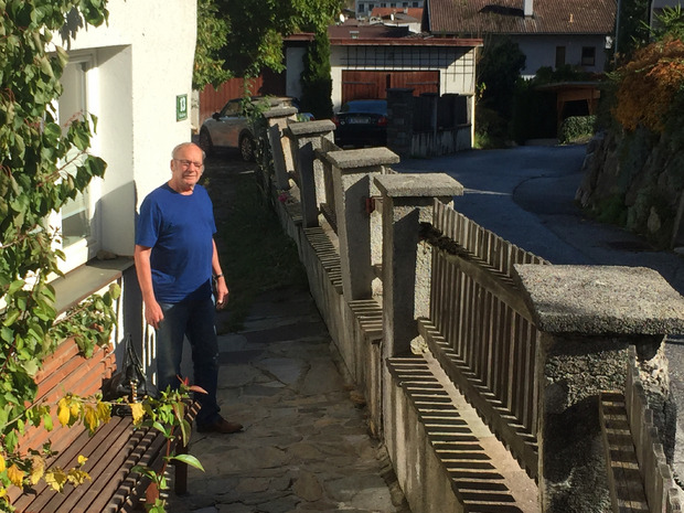 Heinz Schnaiter vor seiner Gartenmauer. Dort, wo die Gemeindestraße bis zum Sockelende aufgeschüttet wurde, neigt sie sich talwärts.